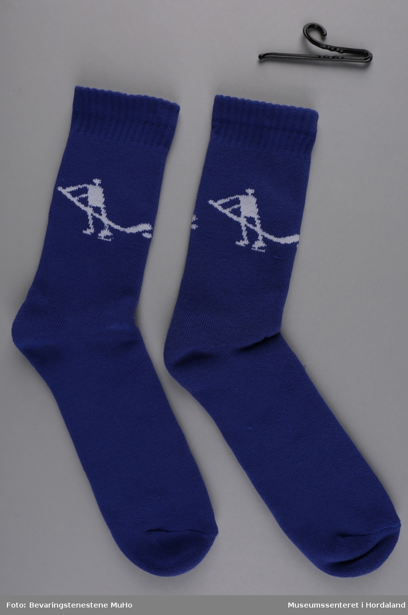 Eitt par blå frottésokkar med kvitt mønster. Mønsteret forestiller ein stilisert mannsfigur (inspirert av hellerisningar) som spelar ishockey.

Sokkane vart produserte til Vinter-OL på Lillehammer i 1994.