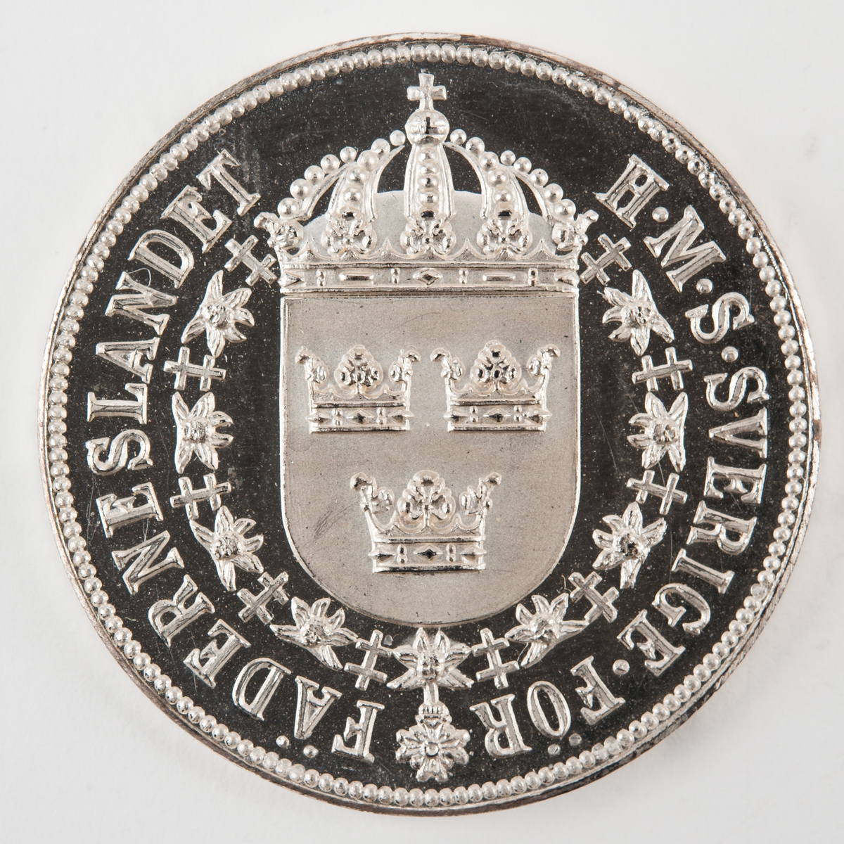 Åtsida: krönt sköld med tre kronor omgiven av serafimerkedjan.