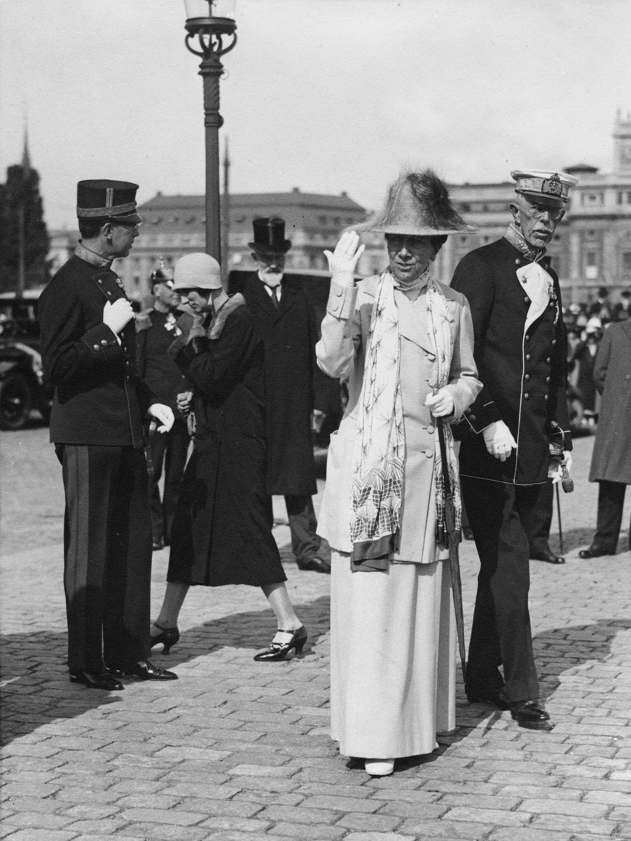 Kung Gustaf V, drottning Victoria och kronprins Gustaf Adolf nedanför slottet. Ibakgrunden Operan och Gustaf Adolfs torg.