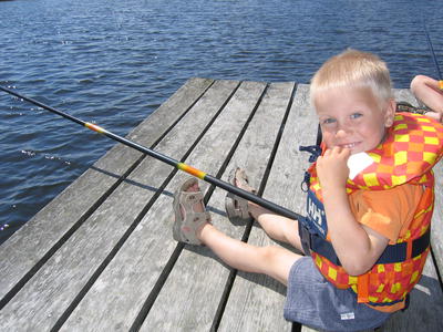 gutt som sitter på ei brygge og fisker. Foto/Photo