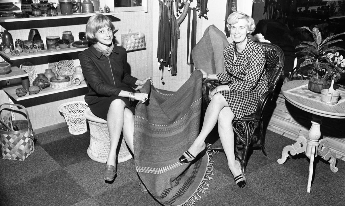 Lärare lärde film, Hantverksbutik, Hans Alsér, Ingenjörer på kurs 18 november 1967

Två kvinnor sitter i en hantverksbutik och håller en randig och mönstrad matta mellan sig. Kvinnan till vänster sitter på en ljus pall och kvinnan till höger sitter i en svart stol med rygg- och armstöd. Kvinnan som sitter på pallen är klädd i en svart jacka, en svart, kort kjol, halsduk och lågklackade skinnskor. Kvinnan till höger är klädd i en ljus, mönstrad klänning och lågklackade skor med två remmar tvärs över vristen.