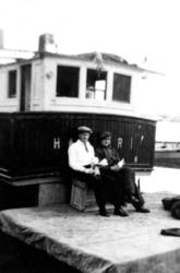 To mann sitter foran styrehus på båt.