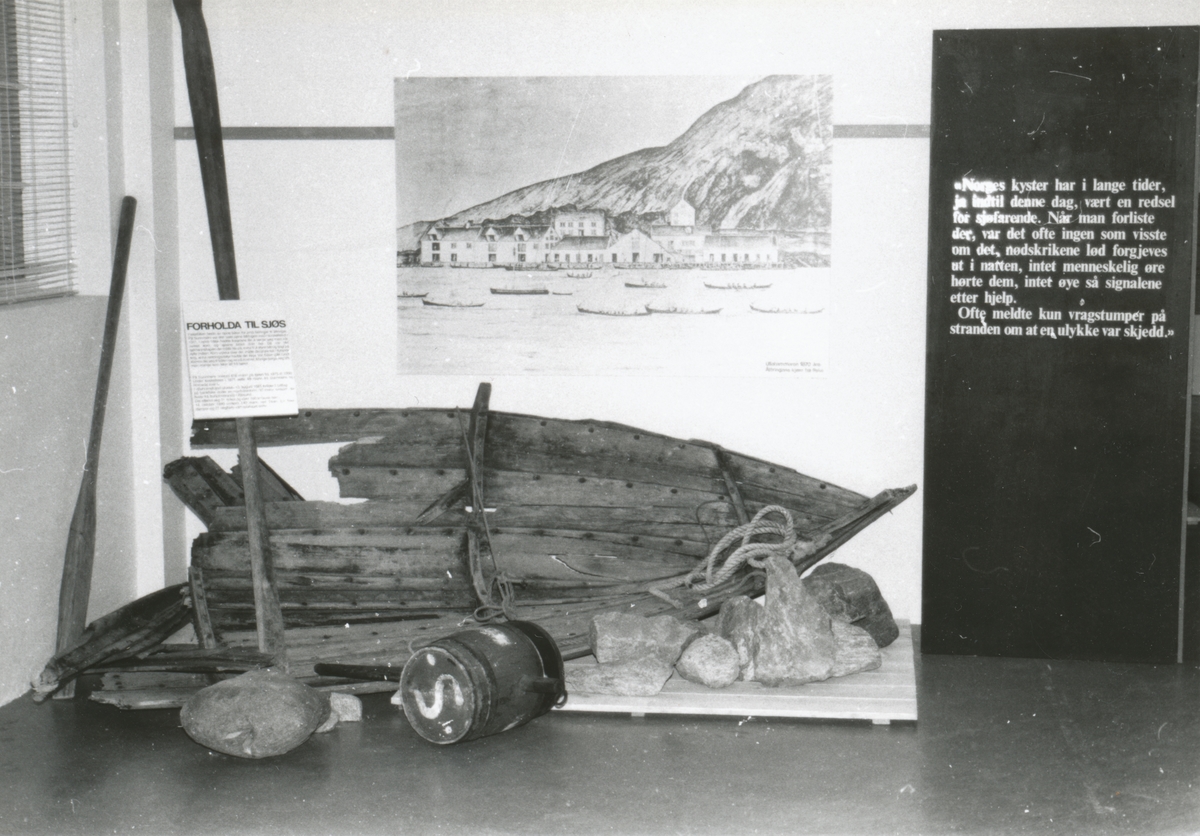 Motiv fra ei tidligere utstilling ved Sunnmøre Museum, Redningsselskapets 100 års- jubileumsutstilling. Utstillingen illustrerer Helge Kragset sin havarerte robåt og stein fra Hakallestranda. I tillegg er der livbøyer, segl og modellbåt.