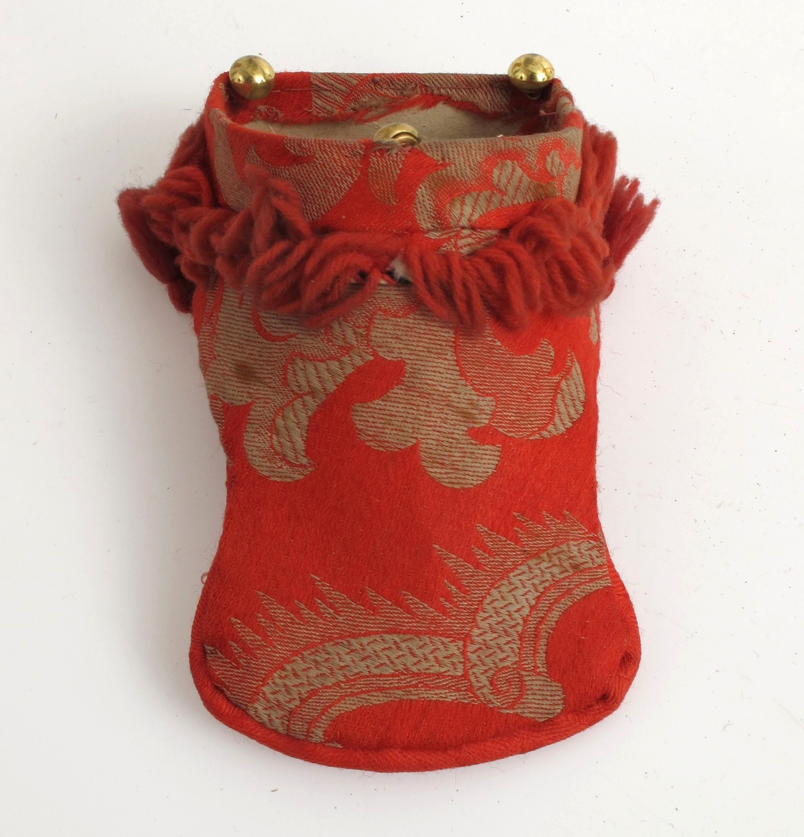 Rød ulldamask, med frynser og pomponger.  Baksiden gråmønstret rødt
