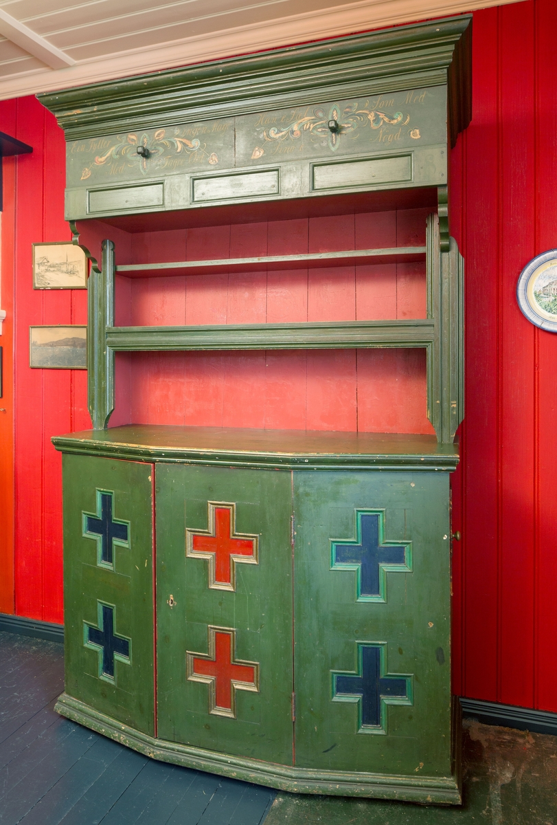 I dør og sider på underskap kryss som er malt.  2 Rosemalte skyvedører m/tekst på skap  øverst, 2 hyller og underskap m/1 hylle. Lite skap i høyre side. Skuff til bestikk.