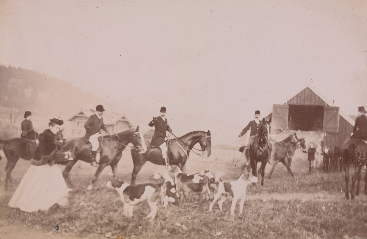Jaktritt, både mannlige og kvinnelige ryttere på deres hester og hunder på gårdsplassen på Linderud.