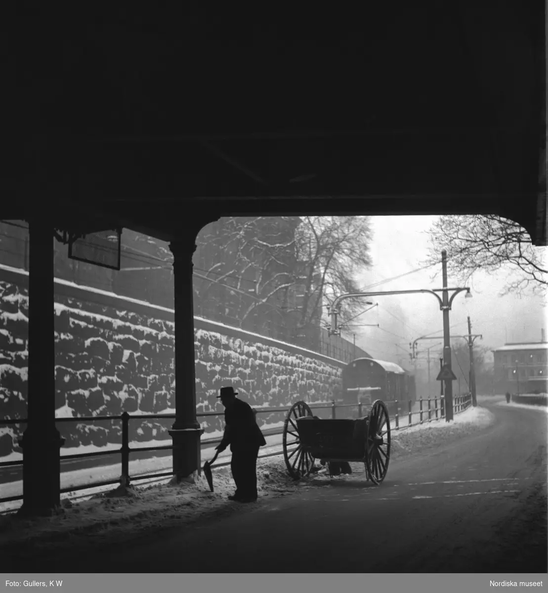 Snöskottare med sin kärra under Riddarholmsbron, Stockholm.