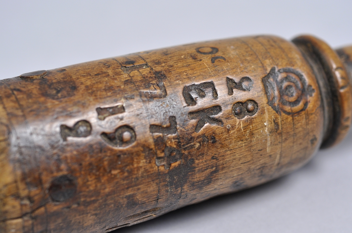 Besman av trä inristat signatur IOS med bly i träklumpen och ett handtag. 
Krönt 2 gånger:
- 1774-02-19  "EK"
- 1775   "AA" 

Komplett med metallkrok och handtag.