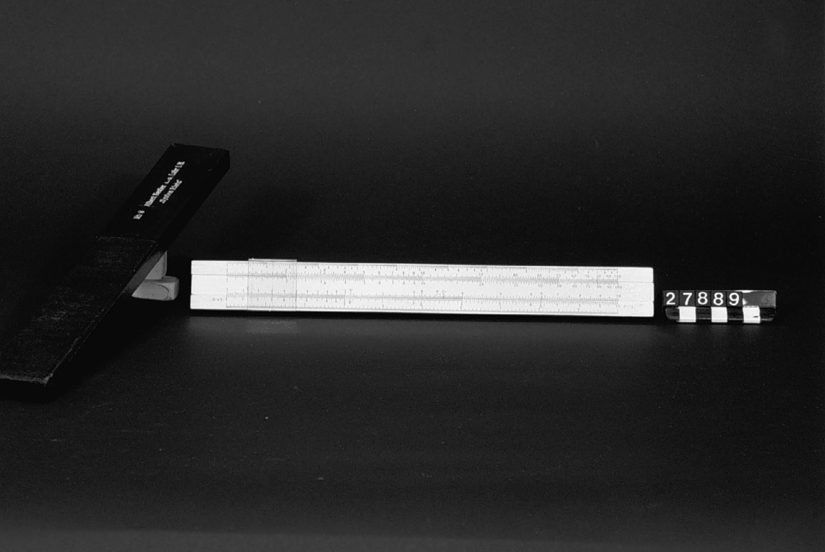 Räknesticka typ nr. 8, med tre logaritmiska skalor, system Rietz, för 1-1000, 1-100 och 1-10 samt engelska tum i 50-delar, på vit lack på trä, i fodral av papp. Tabell med konstanter.