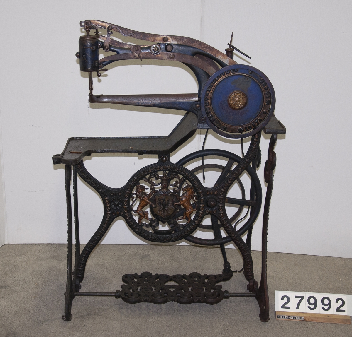 Symaskin, "Patent Elastique" för skonåtling, hand- och trampdriven, på stativ av järn.