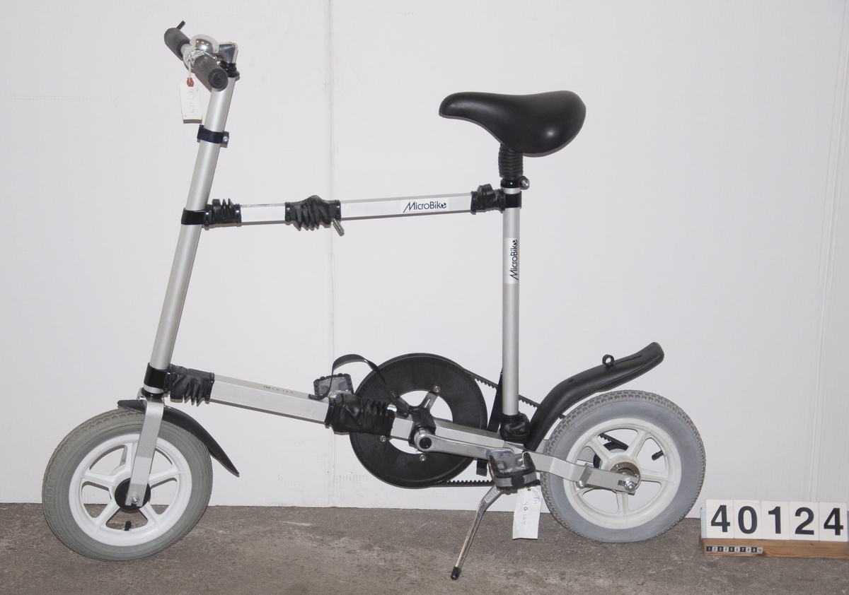 Cykel, hopfällbar låghjuling av plast, gummi och aluminium. Drivs av kevlarförstärkt kuggrem. Hjulbas: 90 cm.
Tillbehör: Fast insexnyckel: 6 mm.