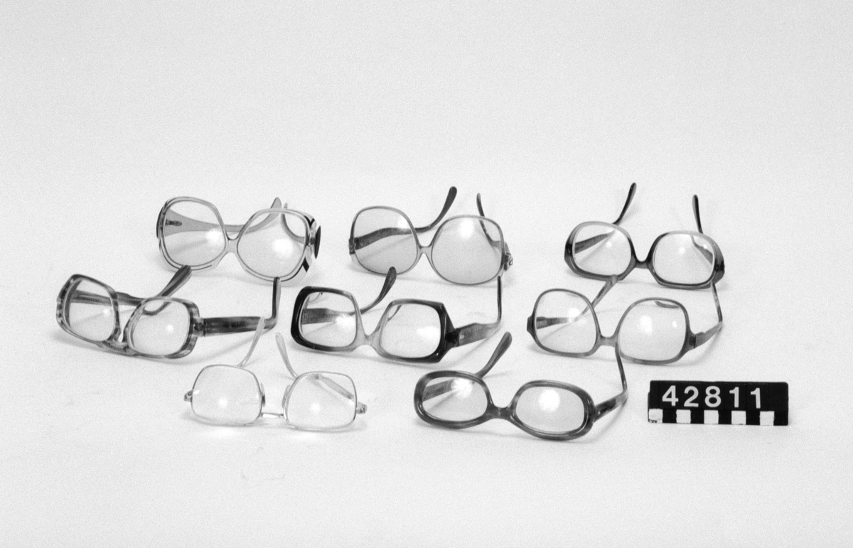 8 par glasögon av plast och glas. Måtten avser de största glasögonen. Glasögonen har bjärta, klara färger och stora ögonöppningar, typiska för tiden. Filos, 3 Christian Dior, Beatrice, Silhouette, Roodenstock Torro WD, ett par utan märkning.