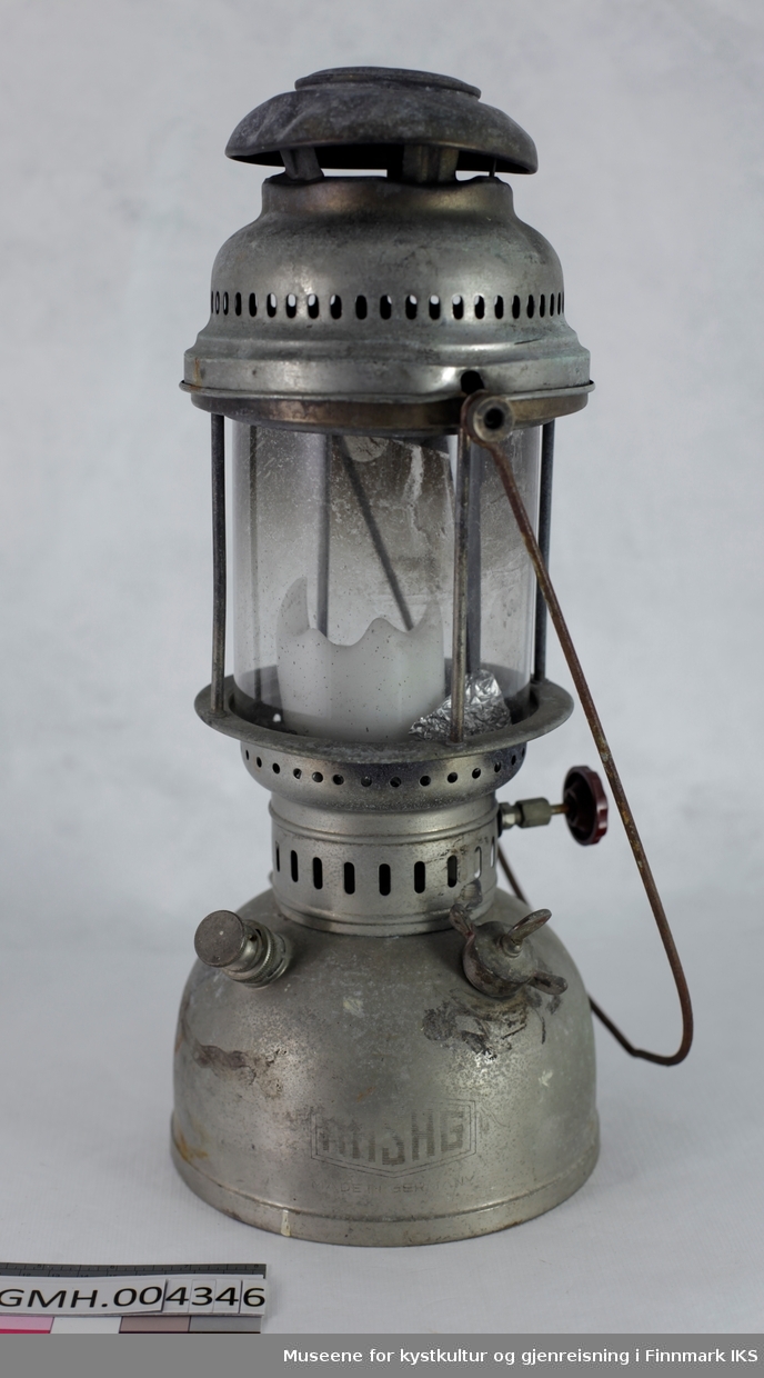 Lampen har en drivstoffbeholder med fyllåpning med skrulokk og en pumpe. Den brukes til å skape trykk i beholderen som så presser drivstoffet gjennom forgasseren slik at den fordampes og forbrennes i en glødestrømpe.  I tillegg befinner det seg et hjul på motsatt side som regulerer strømingsmengden av drivstoffet. Der lyset oppstår er det satt inn et sylindrisk glass. Dette kan ved behov skiftes ved å løse de to skruene som holder håndtaket. Slik kan den øvre delen av lampen løftes av. Lyktet ble brukt med et kubbelys som dekorasjon som står på aluminiumsfolie. Ved overdragelsen av gjenstanden var drivstofftanken fylt med en veske. Den ble fjernet pga. brannfare. Den øvre delen av lyktet er deformert ved en av de festeskruene og kan derfor ikke festes på denne siden.
Gjenstanden er sammensatt av deler fra forskjellige produsenter. Drivstofftanken viser HASAG sin merke mens forgasseren er merket Petromax som viser til Ehrich & Graetz.