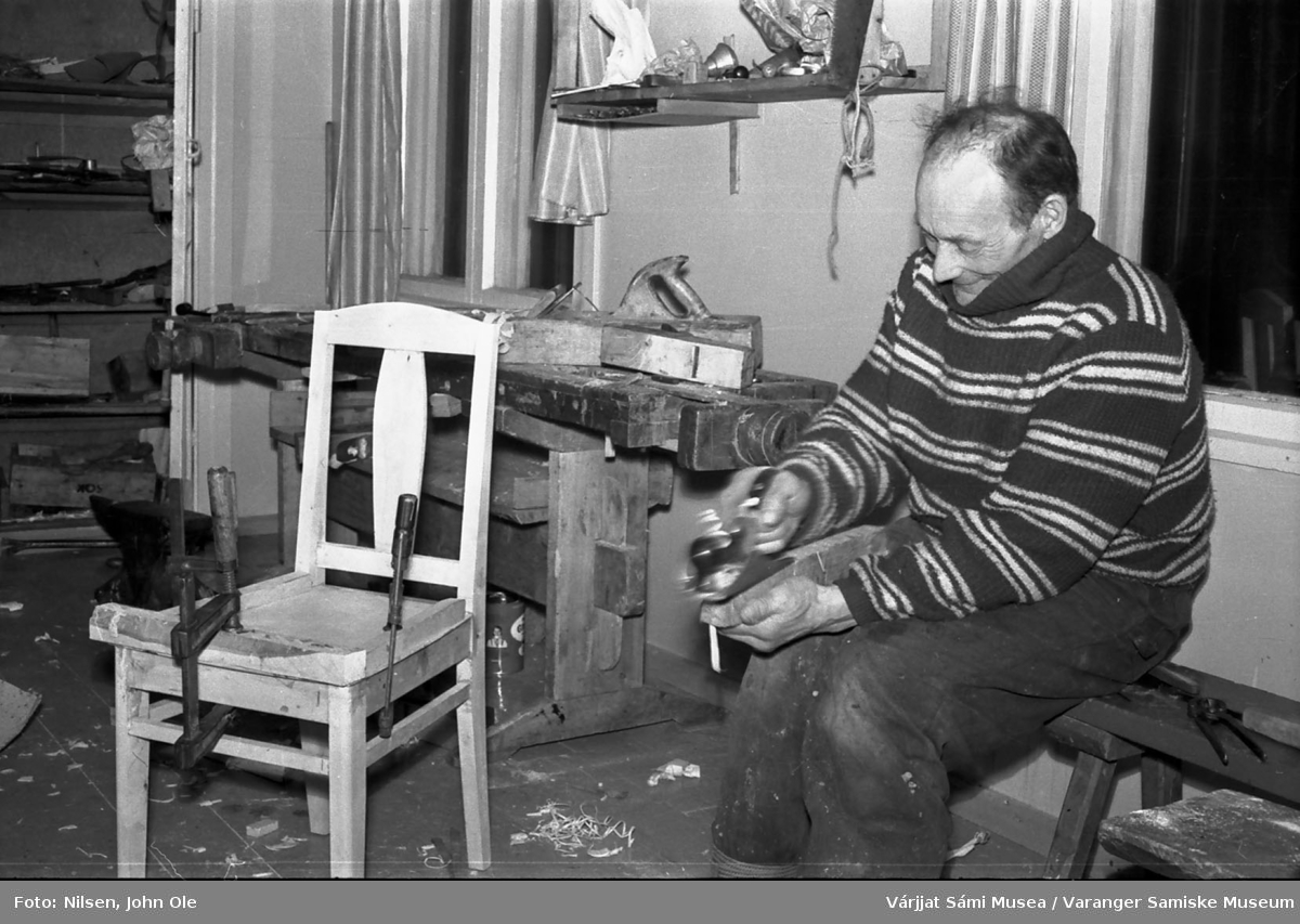 En mann sitter inne i et verksted og høvler på noe. Nuvvus i Finland 8. mars 1967.