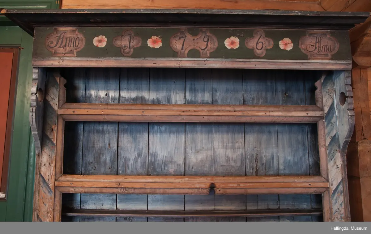 Marmorert toppstykke over felt med fem fyllinger.  Feltet grønnmalt med røde og hvite blomster.  Fyllingene, hvit bunn, sortmalte bokstaver og tall:  Anno 1796 H. Sata.  Overskapet har to hyller med lister og en smal hylle med profilert kant.  Bakveggen hvitmalt med rester etter mørkere undermaling, sideveggene marmorert.  Underskapet tredelt, fremspingende midtparti som er dør.  Fyllinger på de tre delene.  Grønn bunnfarge.  Slitt rosemaling, hvitt og rosa.  Profilert gulvlist.  Nøkkelhull med beslag og defekt lås av jern.  En hylle innvendig.