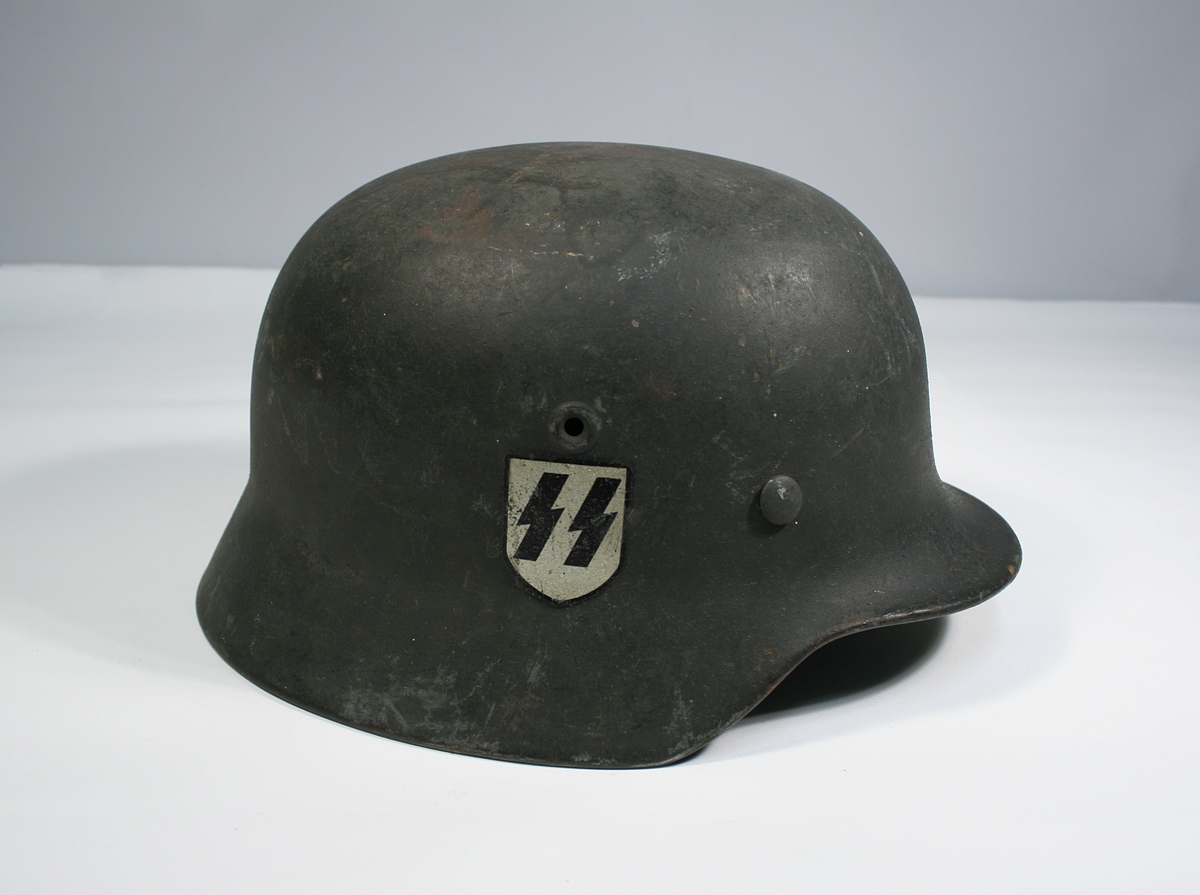 To tyskproduserte hjelmer, en med ørn og hakekors, den andre med SS merke.