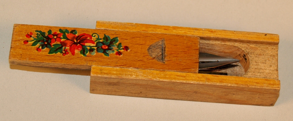 Pennesplittholder med tre pennesplitter. Lokket kan skyvast av. Dekorert med eit blomstermotiv på lokket.
