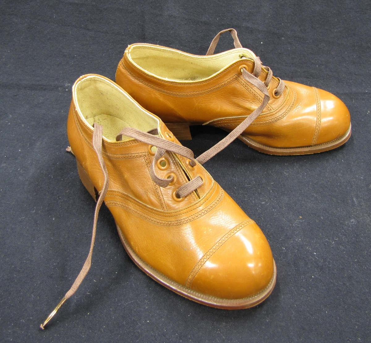 Ett par skor, barnskor, med snörning. Skorna är bruna och på sulans utsida är skorna märkta med A. F. Carlssons skofabriks sigill.