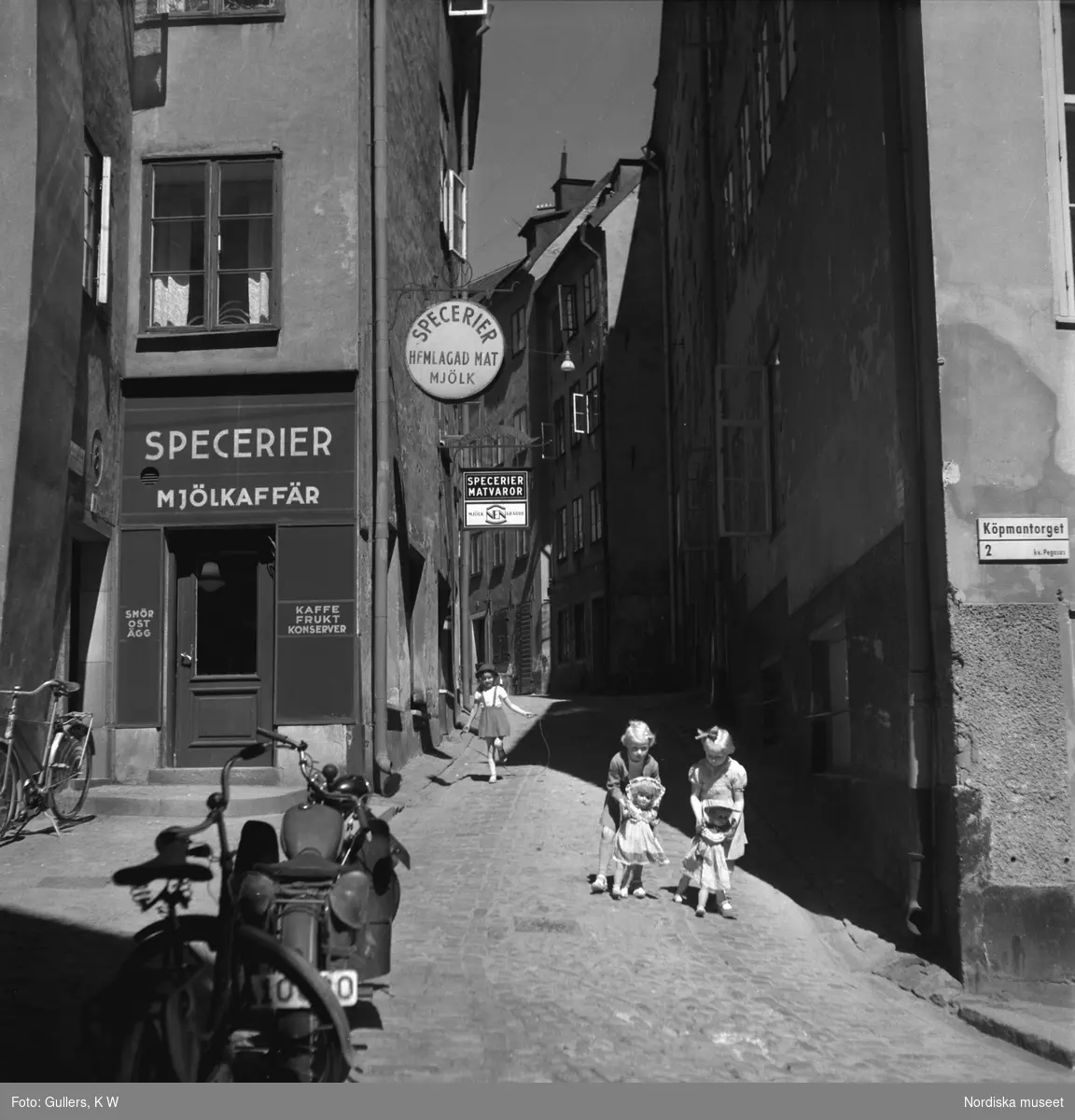 Flickor leker med dockor vid Bollhusgränd / Köpmantorget, Gamla stan, Stockholm