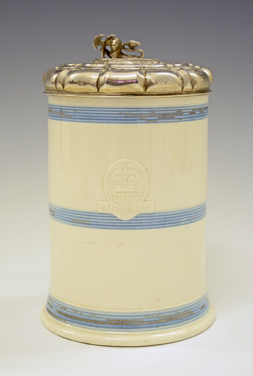 Fra protokollen: 
Steintykrus med sylvlok. Kruset sjølv cylindriskt med 3 blaa, rundu belte paa den kvite glasuren. Framme eit upphøgja felt i eggform med eit tverband yvi med stempla: CR-IV IMPERIAL.
Loket med støypt ciselera løve (med øks i labbane) til lokknapp og uppdriven runding i midten med innfelt sylvpening (medalje merkt F.3, 1659, arm fraa sky høgg av hond som grip etter ei krune). Voluten ikringum bytt med knekkir, og flaten rundt peningen med uppdrivne ciselera granne bandknekkmynster paa mattera grunn. Regence-stil; truleg arbeid av ein bygdesylvsmed (utan stempel). Paa volutknekkine er gravi einstad J. V. B., einstad M. H. D. H. og 1735. Høgd med loket 18,5 cm, tvermaal paa loket 11 cm. Stemp: CM.