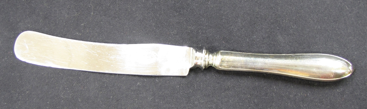 Etui av beige tyg. Foder av röd flanell och fack för knivar, varje kniv i sitt fack. Knivarna är numrerade VM17217:1-12. Etuiet är broderat i rött: ''Matknivar''.
Inköpt hos Knutssons Antikhandel i Vänersborg.