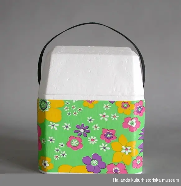 Rektangulär kylväska av frigolit. Lock. Svart textilhandtag. Väskan klädd med blommig plast i flera färger.