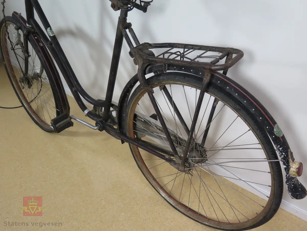 Tråsykkel, damemodell. Har to hjul, styre, sete, pedaler, frontlykt, ringeklokke, bagasjebrett, dynamo og refleks bak. Svart med rød staffering. Brunt sete og røde holker på styret. Sykkelen er i hovedsak lagd av metall, gummi og skinn.
Emblem med teksten: REIDAR KVAM Ø. GAUSDAL MIL.