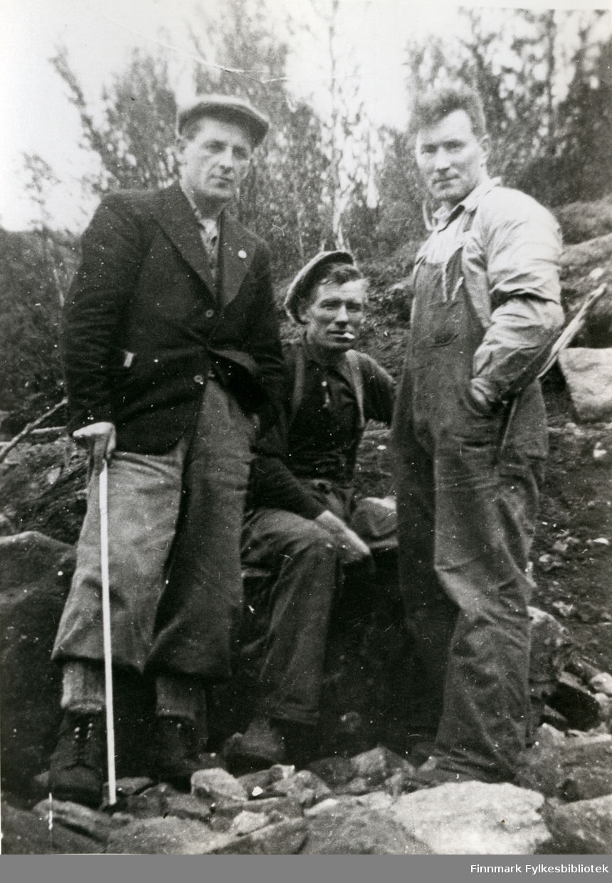Bildet viser fra venstre oppsynsmann John Svendsen, Arthur Dagenborg og Sverre Pedersen. Dagenborg sitter på en stein flankert av Svendsen og Pedersen stående. De to arbeiderne har arbeidsantrekk, mens oppsynsmannen har en dressjakke på seg.