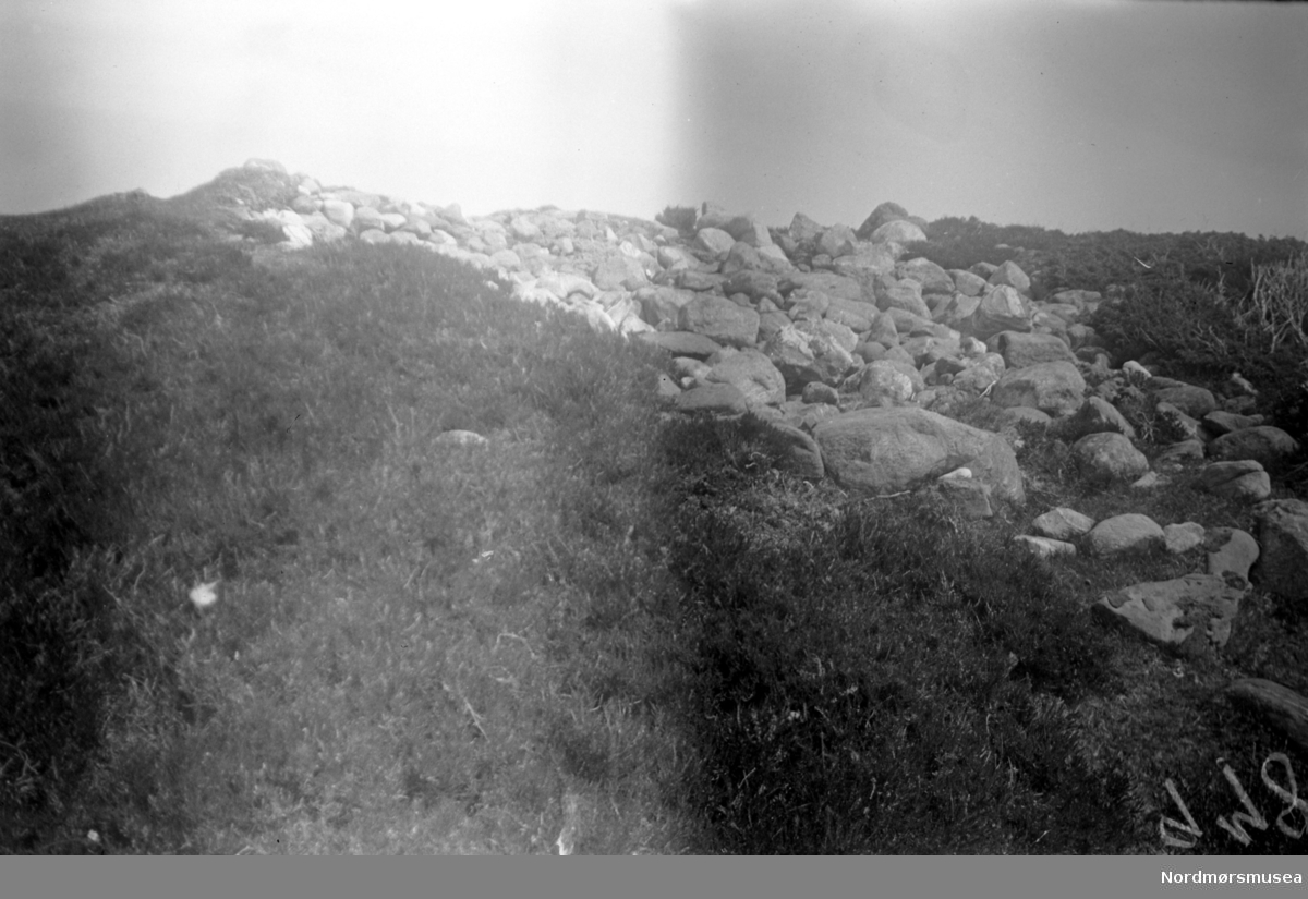 På bildet ser vi en gravrøys nord for Edøyvalens havbukt, nær Kulisvaet på Edøy. Se Yderstads notater, Bind 7. side 346, nummer 9. Bildet er datert Juni 1948, og mest sannsynlig den 16. denne måned. Nordmøre Museums samling