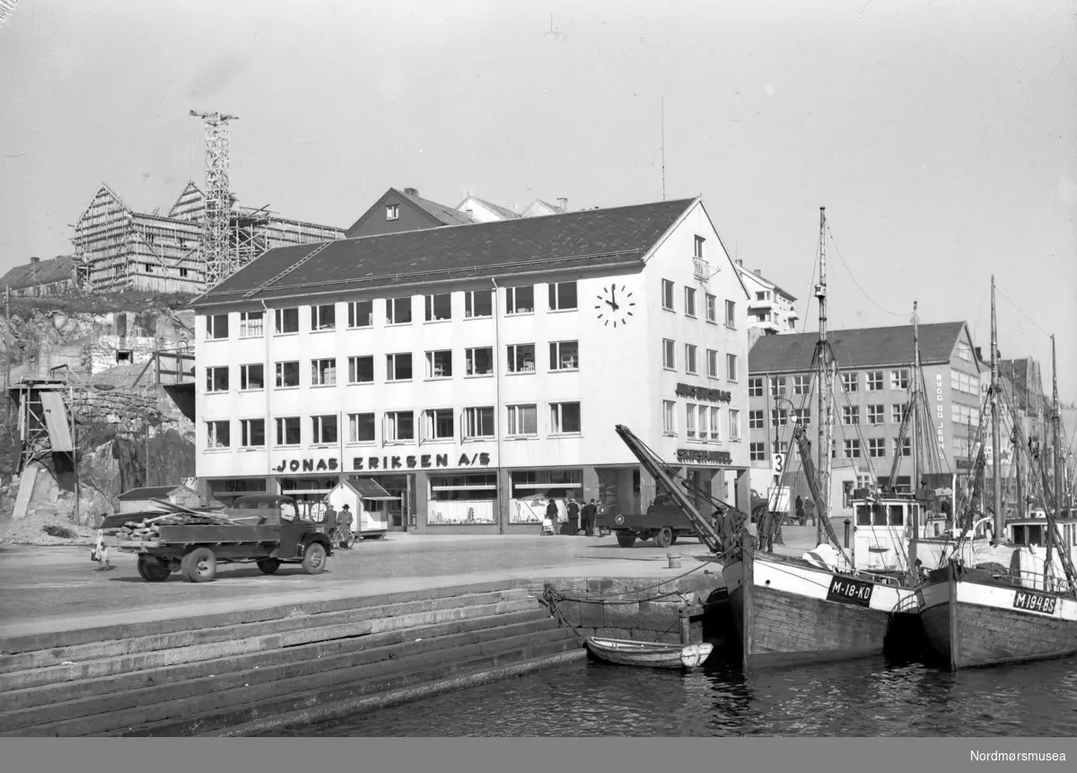 Bildet viser på to motorskøyter ved Vågekaia utenfor Jonas Eriksen skipshandel (pr 2017 servicetorget) i Kristiansund.
Den innerste skøyta heter M/K "Rayon" M-18-KD og hadde følgende hoveddimensjoner:
L= 50 fot. x B= 14 fot. x D= 8 fot og har en tonnasje på 25 BRT/ 8NRT og bygd i tre i 1919. Ombygd i 1947. Hun har en Brunvollmotor på 56 hk og eier er: Harald Johansen, Vevang, Averøy.
Den ytterste av skøytene er M/K "Haugen" M-194-BS som hadde følgende hoveddimensjoner: L= 40 fot. x B= 12,5 fot. x D= 6,5 fot og bygd i tre i 1935.
Hun hadde en Albinmotor på 75 hk fra 1959 og eier er: Peder M. Hoel m. fl., Henda, Averøy.
Ellers ses en kaikanten (stein?) av typen som ble laget på A/S Storviks Mek. Verksted på Dale ved Kristiansund. (info Peter Storvik) - 
gjenreisingen av Kristiansund etter krigen. bygging i Hauggata. Sentralt i bildet sees det nye Jonas Eriksen-bygget, innviet 8. desember 1947.  lastebiler, kran, robåt, fiskebåter  Fra Nordmøre Museum sin fotosamling, Williamsarkivet.