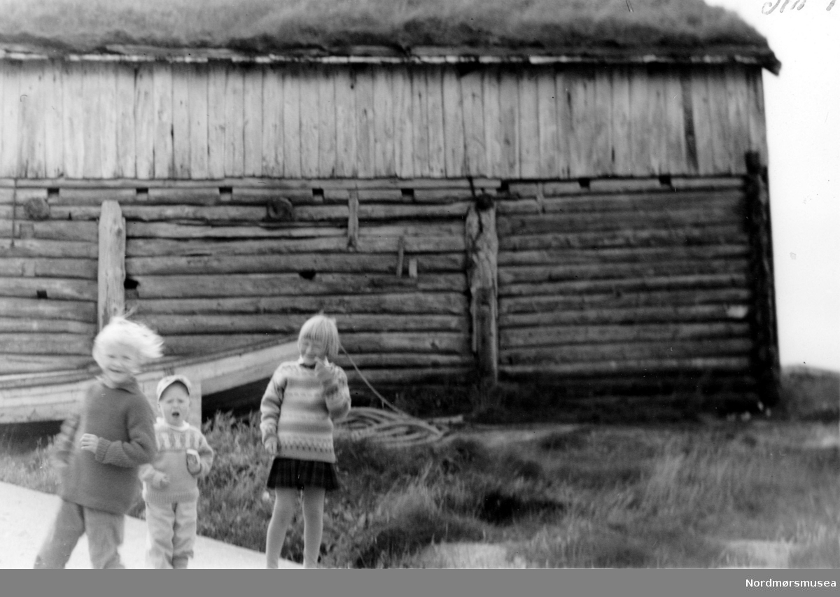 Tre barn foran et stort naust. Fra Nordmøre museums fotosamlinger. EFR2015