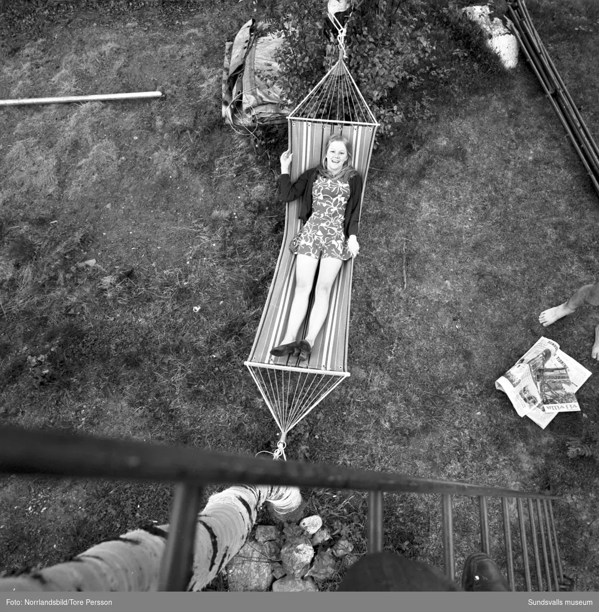 En kvinna ligger i en hängmatta, fotot taget uppifrån från en stege. Bilden tagen till en annons för Skogsägarföreningen.