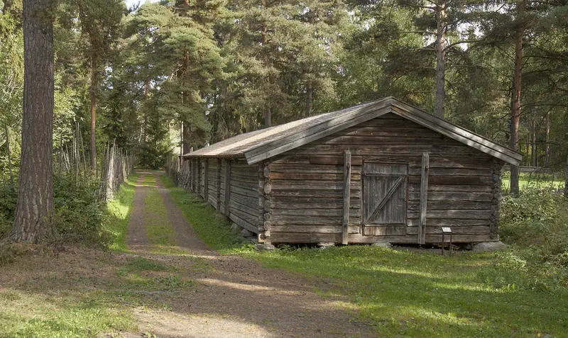 Fjøs i grått tømmer, med dør midt på gavlveggen.