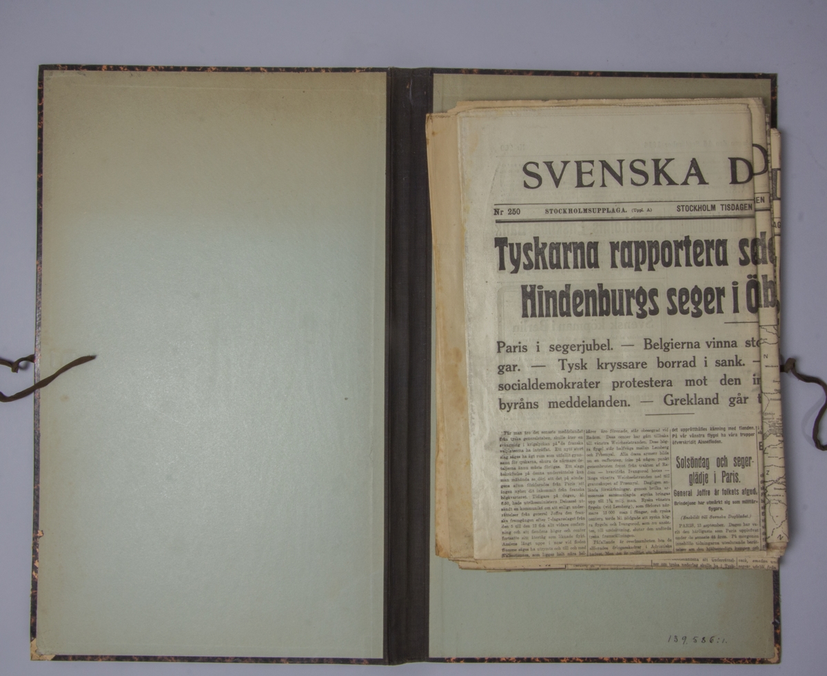 Portfölj av marmorerad papp. Sammanhållen med knytband. Rygg av svart linne. Innehåller enbart flera exemplar av Svenska Dagbladet från 1914.