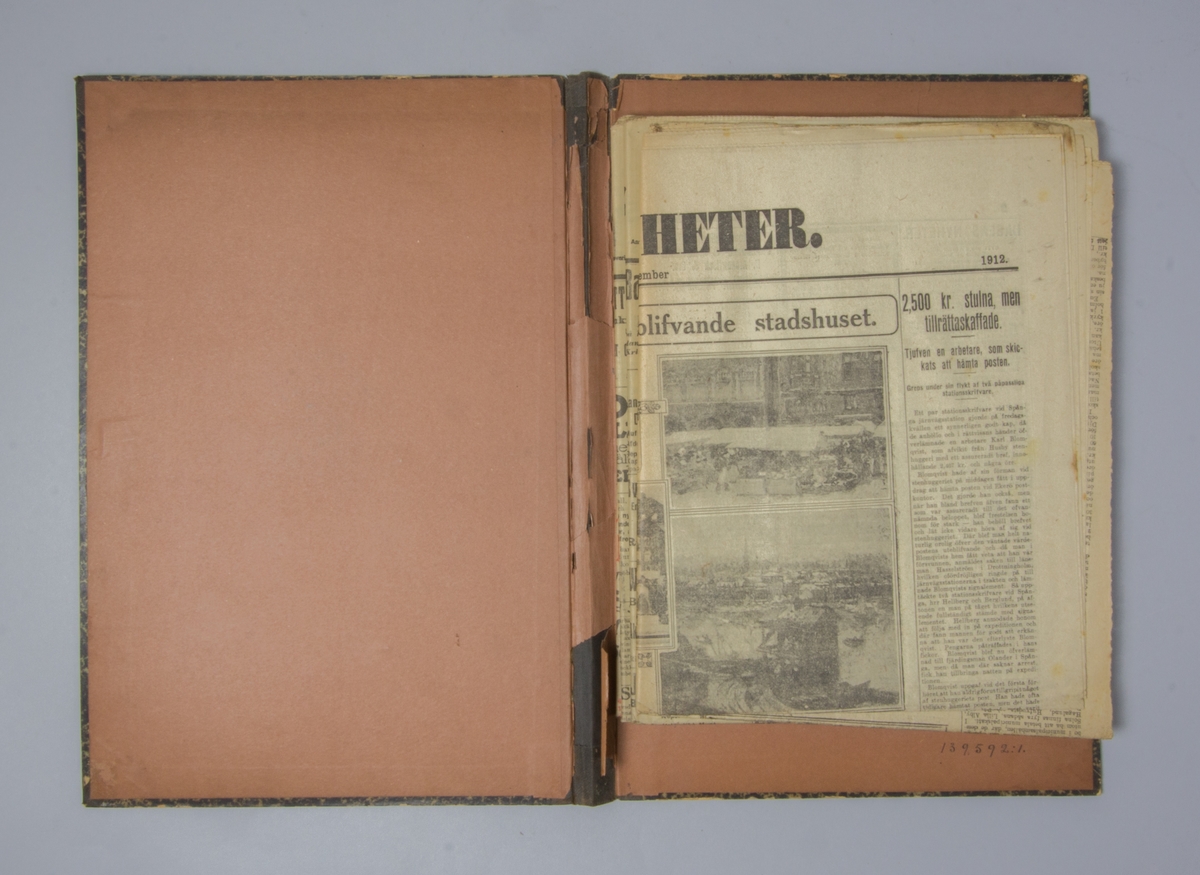 Portfölj av marmorerad papp. Sammanhållen med knytband. Rygg av svart linne. Innehåller enbart flera exemplar av Stockholms dagblad och Dagens Nyheter från 1912 och 1914.
