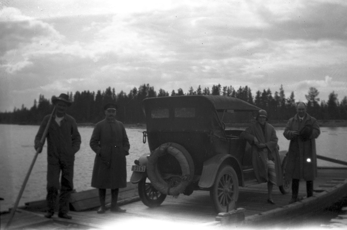 David Brundin hälsar på Elis Öhrn, som står vid färjekarlen till vänster, i chaufförsmössa. Elna och David Brundin till höger. Bilen en Overland 1924 med 4 cylindrar.