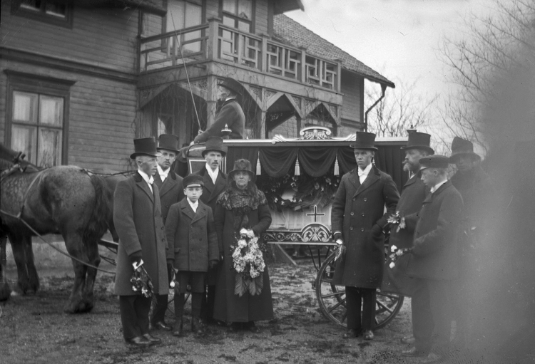 Familjen Fors med släktingar står uppställda vid en likvagn. 
Begravning efter Karin Fors (1897-1919), avliden i "spanska sjukan" i april 1919. Syster till Agda Bergqvist.