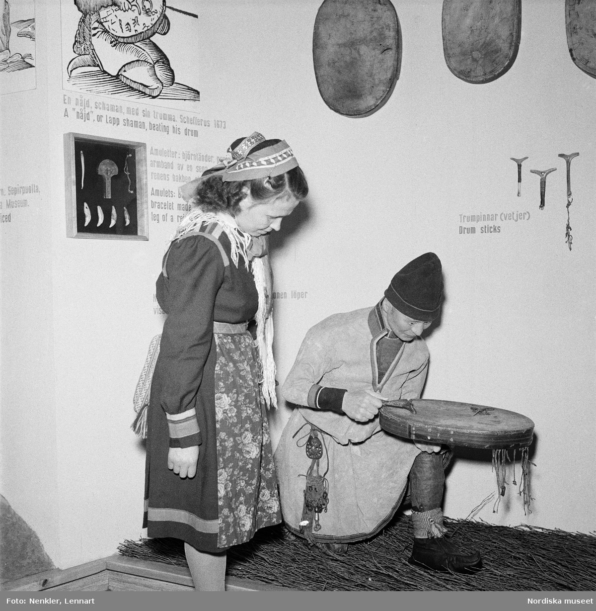 Motiv från Skådesamlingens öppnande på Nordiska museet 29 maj. Ester Sarri studerar en monter med dräktdocka föreställande same hållande trumma.