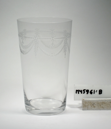 Grogglas. 
Konande glas.
Pantograferad dekor.
Ofärgat klarglas.
Inskrivet i huvudkatalogen tidigast 1990.
Funktion: Grogglas