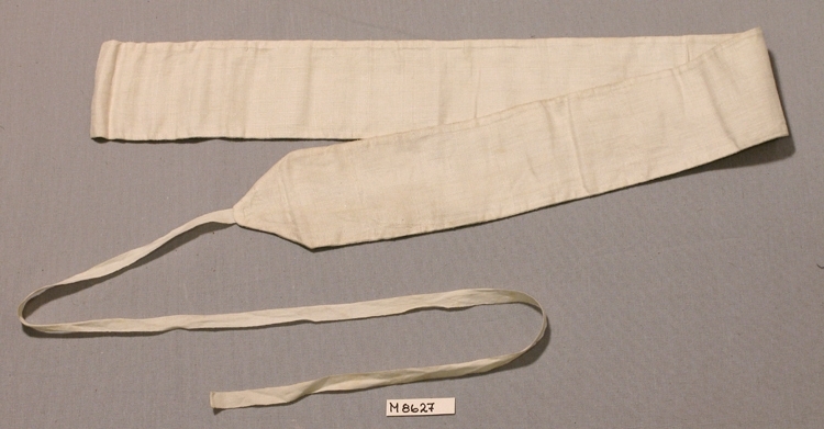Linda av vitt linne, dubbel.
Långsmal med en spets i ena kortsidan, i själva spetsen 
sitter ett fastsytt band (760 x 10 mm.) för knytning.

Inskrivet i huvudbok 1936.