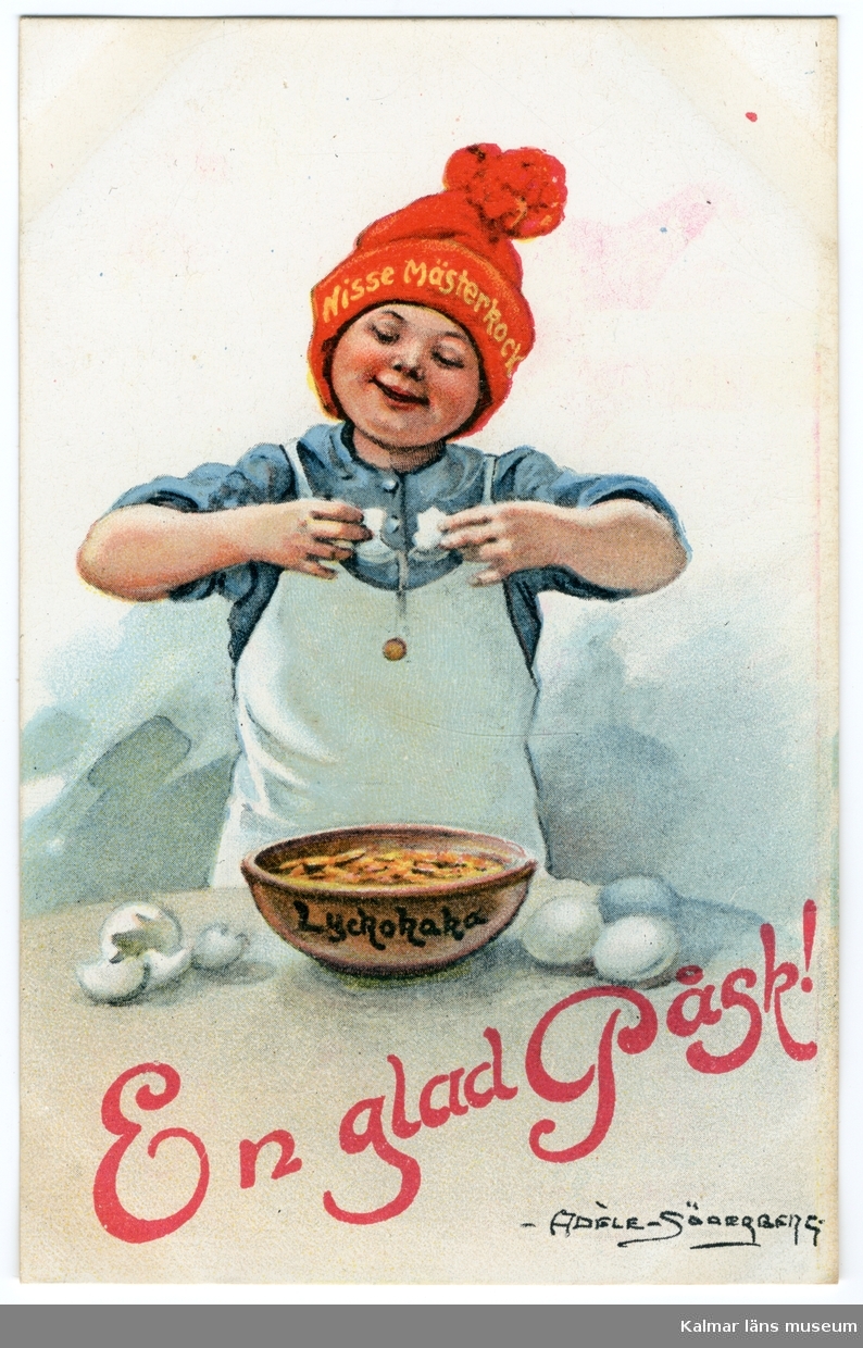 En pojke, tomtenisse, står och knäcker ägg i en skål. På skålen står det Lyckokaka. Han har en röd luva på huvudet där det står Nisse Mästerkock med gula bokstäver framtill.