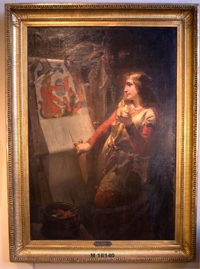 Oljemålning på duk.
Ung kvinna  i vikingakläder framför en stående vävstol.