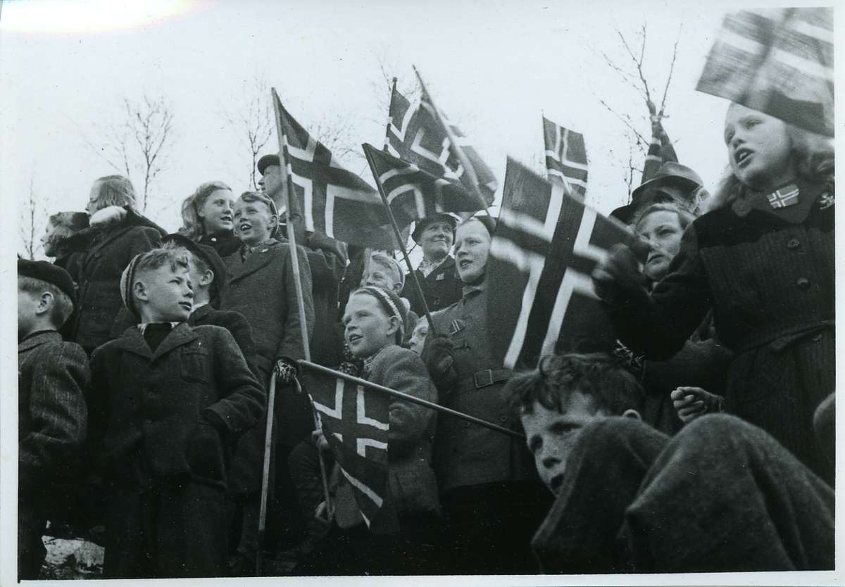 Tusenvis av folk har møtt fram for å ønske de norske polititroppene velkommen til Narvik. Barn med flagg.