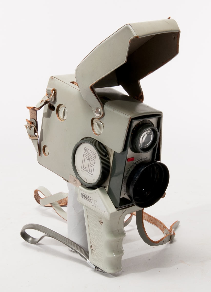 Filmkamera Eumig typ C6, med zoom mellan 6/12,5/25 mm, som kan motorstyras via tillhörande handgrepp Eumig C.
Objektiv Eumig 504, 1:1,8 F=8-25

Med grönt läderhölje.