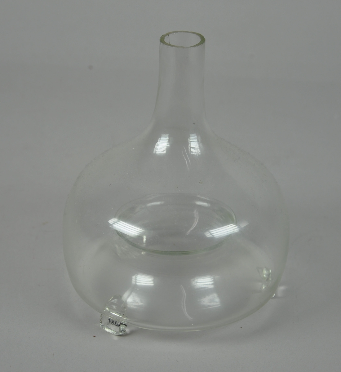 Fluefanger av glass formet som en flaske eller en karaffel med åping i bunnen. Den har tre glassbein.