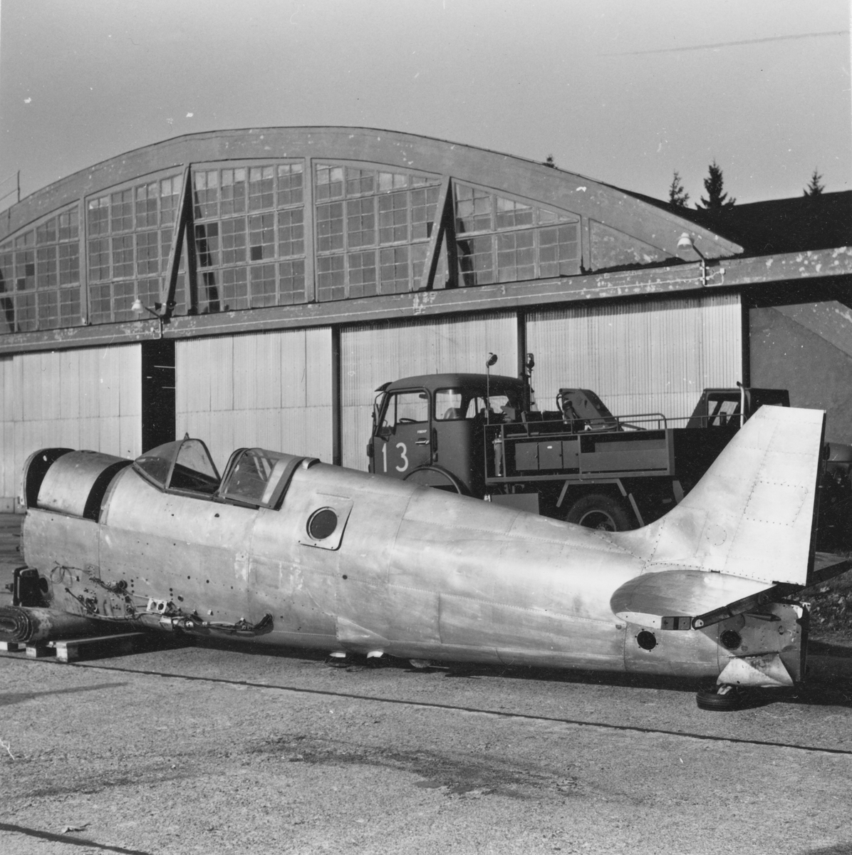 Kroppen till flygplan Spitfire står utanför en hangar på F 3 Malmen. Flygplanet har just anlänt från Kanada i transportflygplanet TP 84.