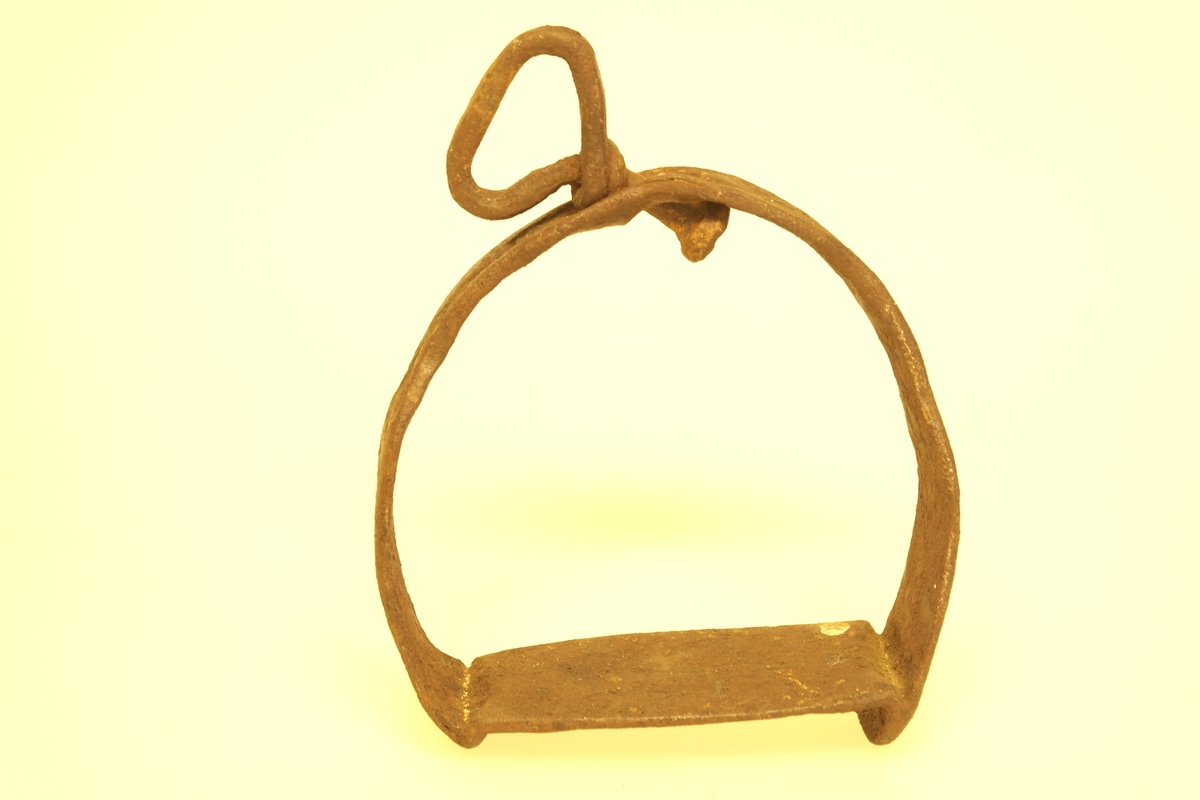 Hesteskoformet stigbøyle av smidd jern. Fotplaten er rektangulær.