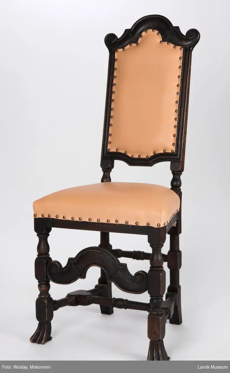 Høyrygget stol uten armlener med skinntrekk på sete og rygg.