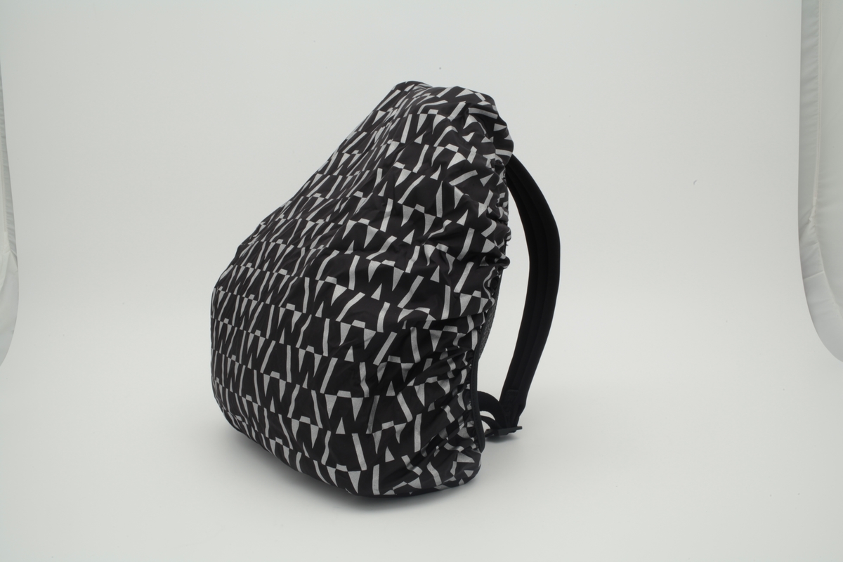 Liten sekk for trening. Sydd av nettstoff, der det ytre stoffet er laminert med flere lag nettstoff, og kjernen antagelig selvlysende, dvs av lysegrå refleksfibre. Sekken består av ett hovedrom og et lite ytterrom. Nedre del av både sekk og ytterrom er av tett neopren. Selve bunnen har en påsydd plate av gummi, med 4 "ben" i form av logoen "AW".  Innvendig bunnplate er imidlertid både bredere og lengre og av ukjente materiale. Sekken er flat nederst og buet i overkant, hovedrommet åpnes nesten helt ned i begge sider og lukkes med grov plastglidelås. Ytterommet åpnes i overkant og lukkes med tilsvarende glidelås. Innvendig er rommene fôret med et ekstra lag, enkelt nettstoff, og hovedrommet utstyrt med en ekstra lomme. Selene er regulerbare med spenner, er polstret, av neopren og utvendig forsterket med påsydde bånd av bevernylonlignende materiale ivevd "WANG" gjentatte ganger. Tilsvarende stropp øverst, til bæring i hånden. Under selefestene en ekstra lomme, lukket med samme grove glidelåstype. Nedi lommen ligger et påsydd regntrekk av tynt, vannavstøtende matriale, med påtrykt "AW" i et sammenhengende mønster utført i lysreflekterende trykkfarge over det hele. Med påsydd elastikk langs ytterkanten, kan trekket raskt tas ut og vikles omkring sekkens front og holde seg på plass i regnvær. Alle glidelåser er utstyrt med en "drastropp" av det sorte bondet ivevd WANG.