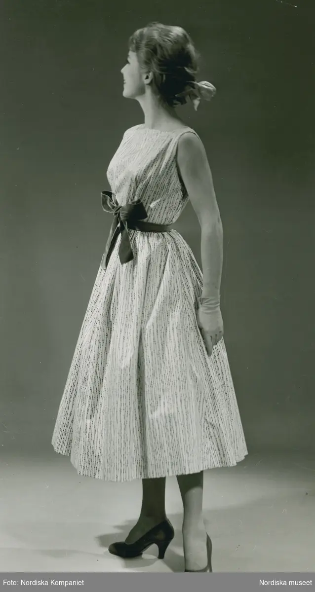 Brud och Hem. Modell i klänning med linjeprickar och rosett, handskar och band i håret.